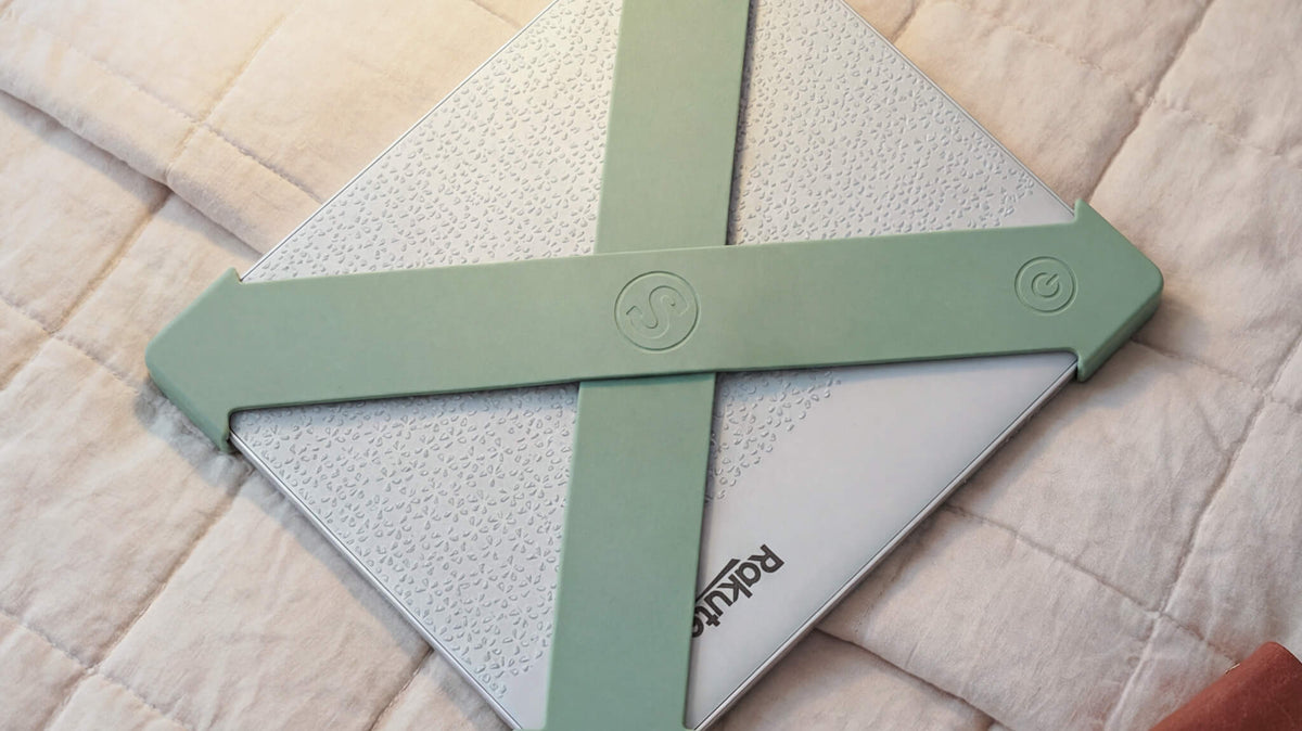 Reader holding a Kobo Libra one-handed with sage green Strapsicle straps - no pinch grip needed