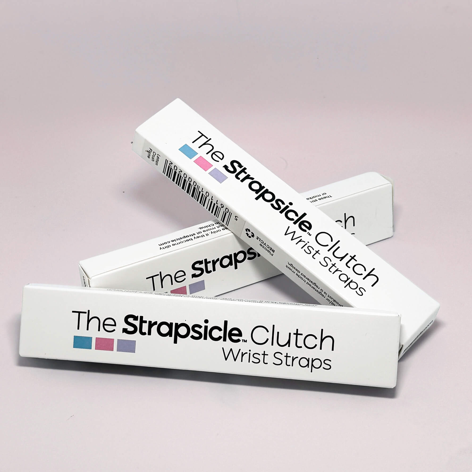 Boxes of 'The Strapsicle Clutch Wrist Straps' on a light pink background