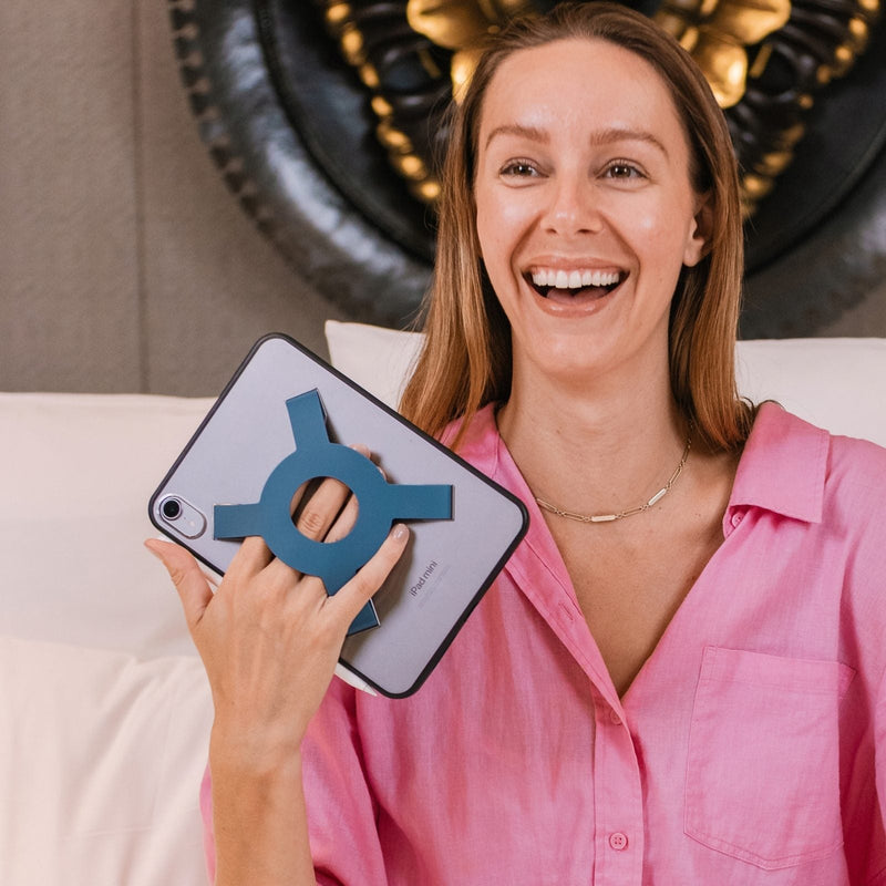 Woman smiling holding an iPad mini with the Strapsicle case all-groups
