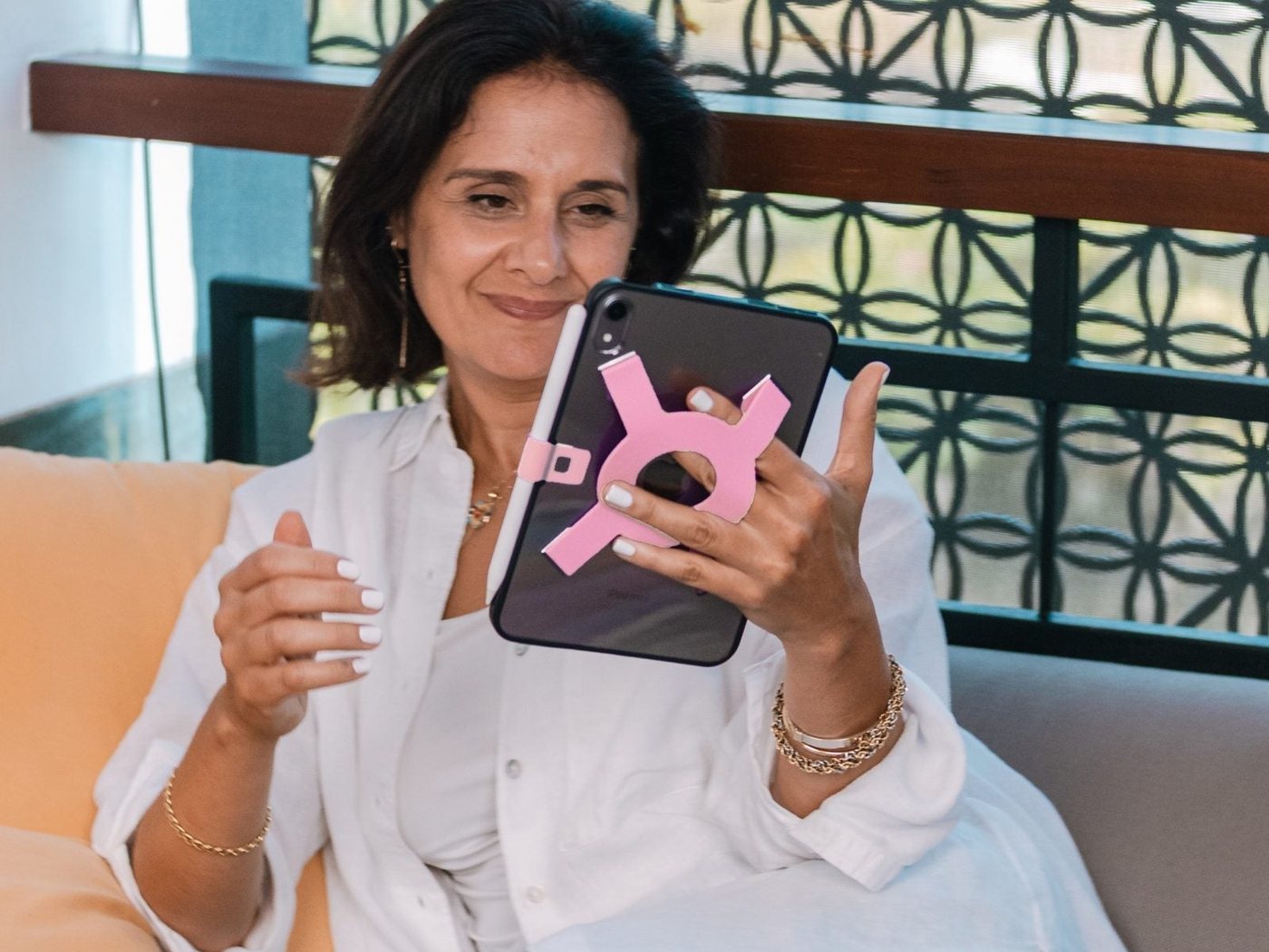 Woman smiling at her iPad mini, held with the Strapsicle grip