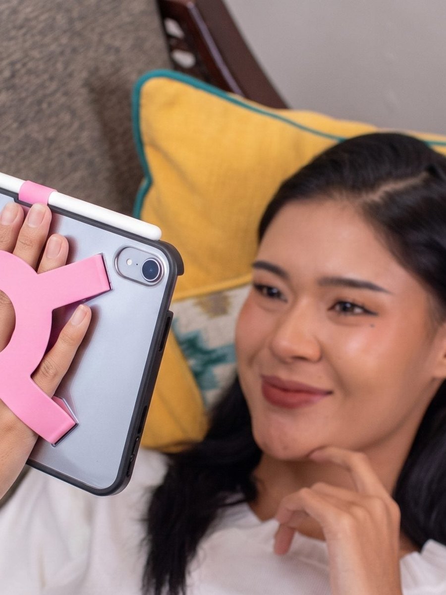 Woman relaxing on a sofa holding an iPad mini with the Strapsicle case
