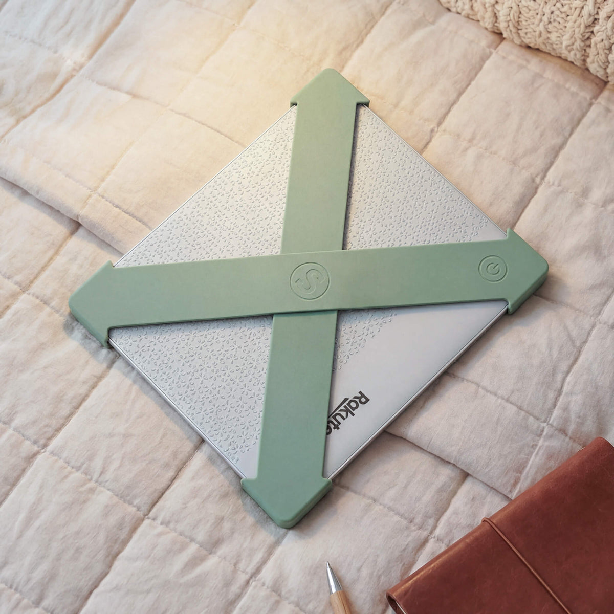 Reader holding a Kobo Libra one-handed with sage green Strapsicle straps - no pinch grip needed