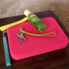 Pink clutch with keys and hand sanitizer on a wooden surface