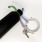 Black water bottle with a green cap, purple keychain, and silver key on a white background