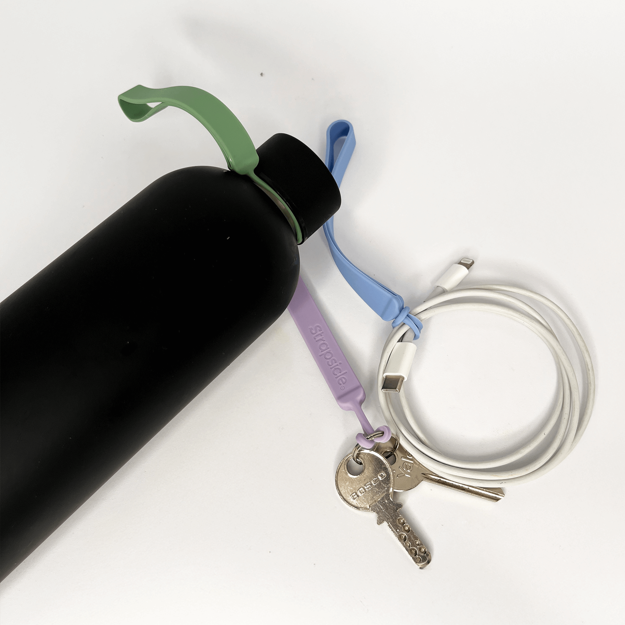 Black water bottle with a green cap, purple keychain, and silver key on a white background