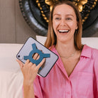 Woman smiling holding an iPad mini with the Strapsicle case all-groups